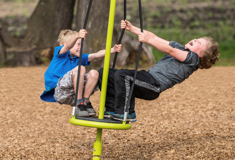 kids playing on playground equipment with engineered wood fiber underneath