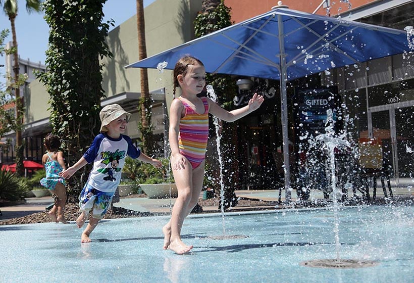 kids run through the water on a splash pad