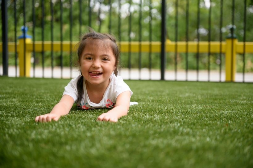 child lays on synthetic turf 