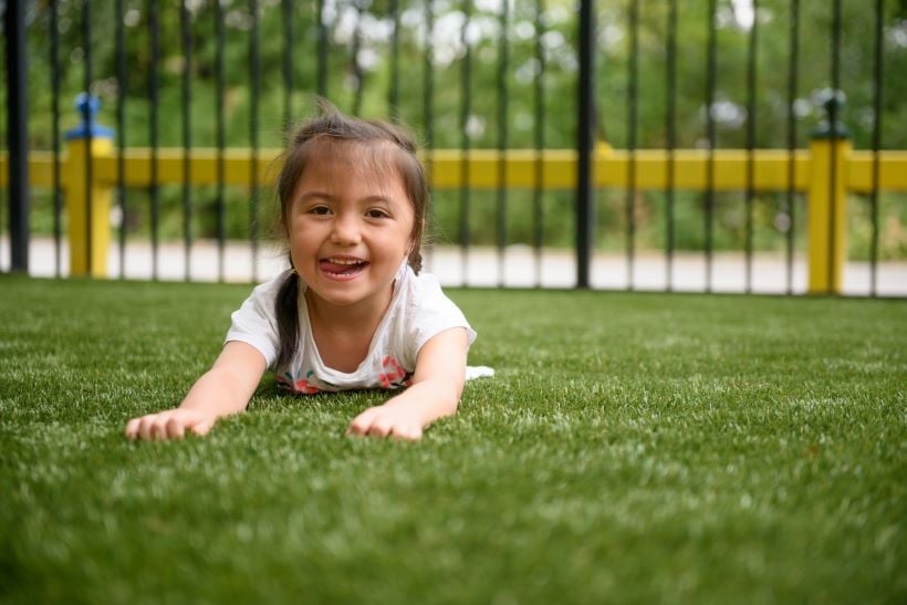 child lays on synthetic turf