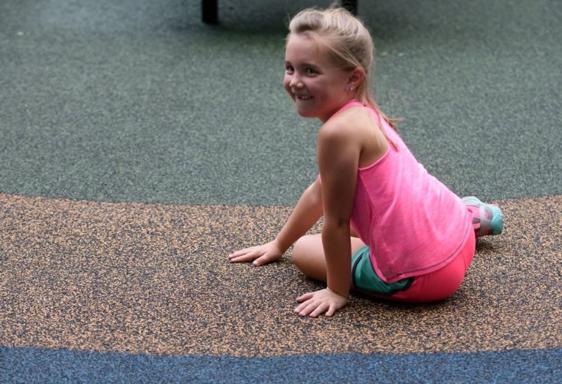 Child sitting on Poured in Place Surfacing